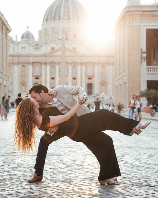 Couple kissing in a dramatic dip in St Peter’s Square, with St Peter’s Basilica behind them