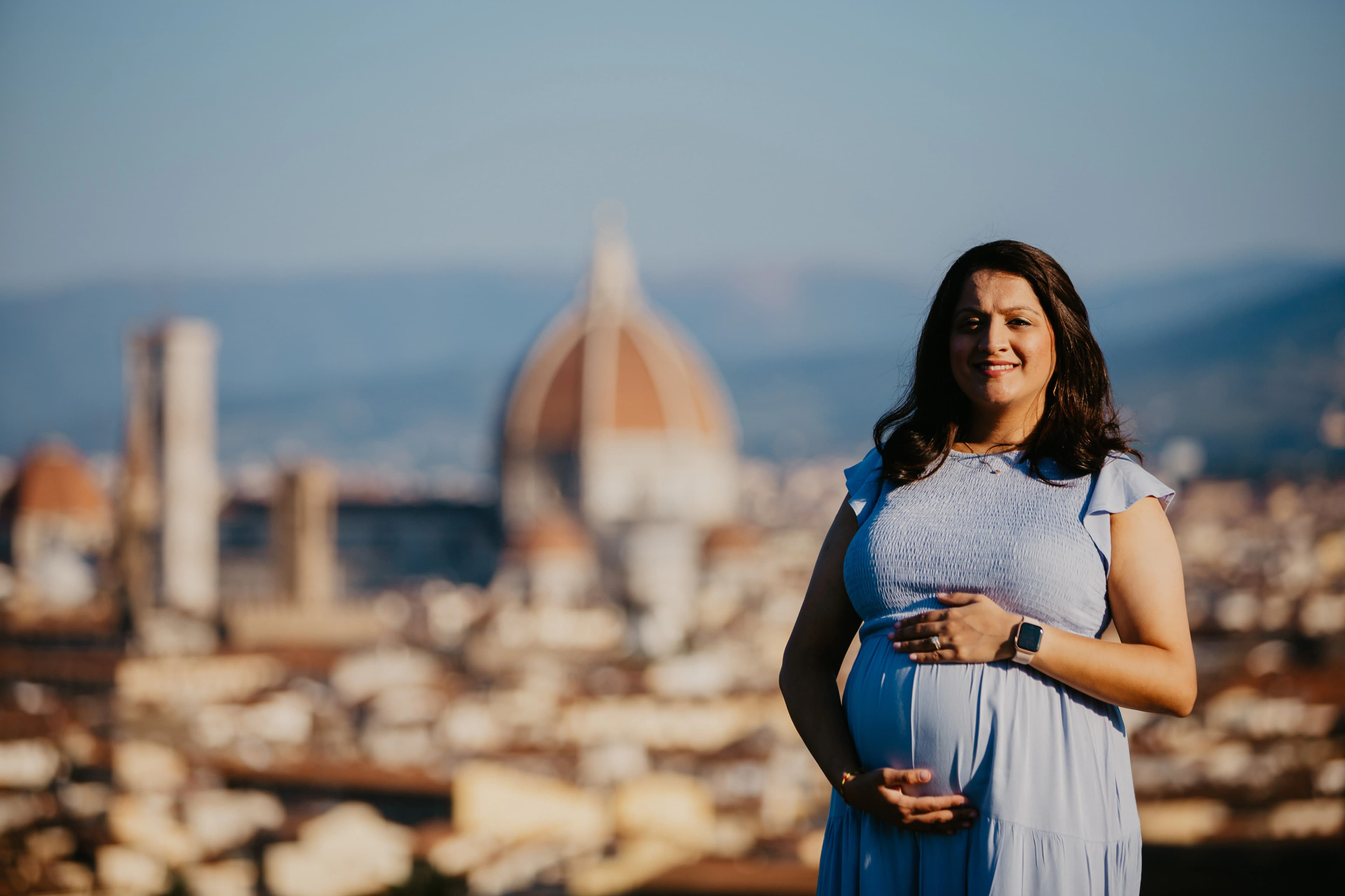 Pregnant woman standing before Florence’s skyline, with the Cathedral of Santa Maria del Fiore and its dome visible behind her